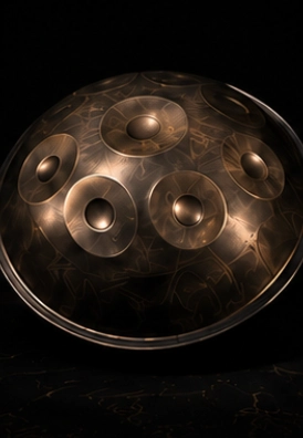 Metallic handpan drum on dark background.